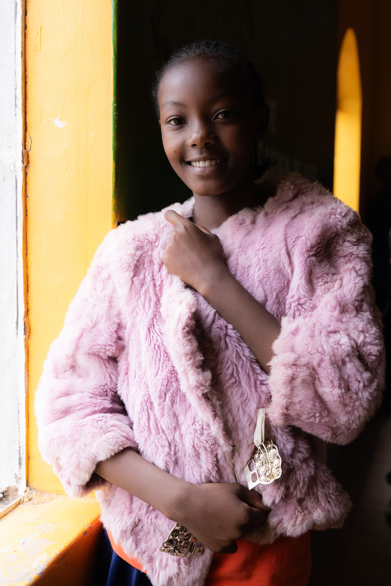 Young model in pink fur coat by a golden window