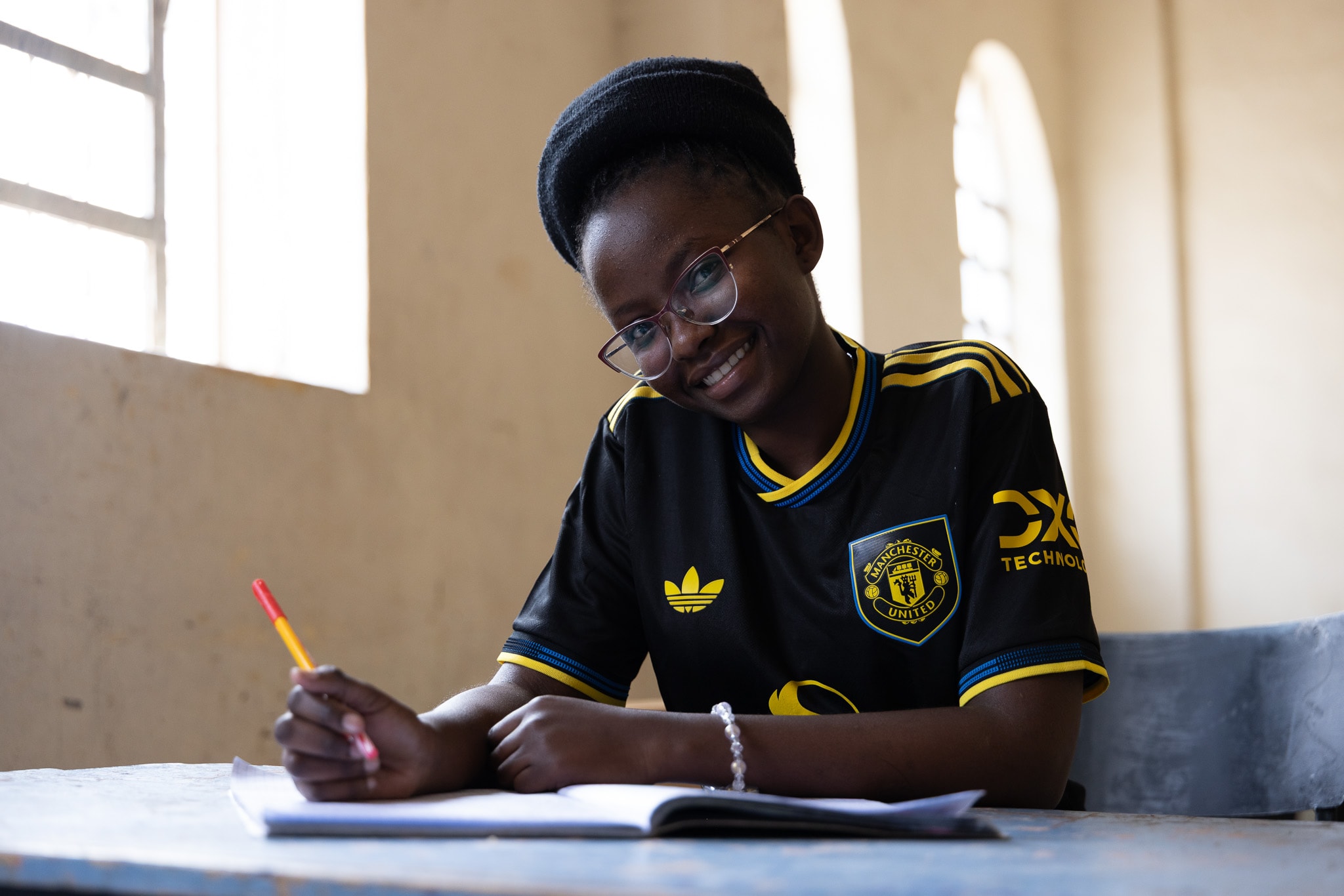 Student writing at a desk, Manchester United jersey
