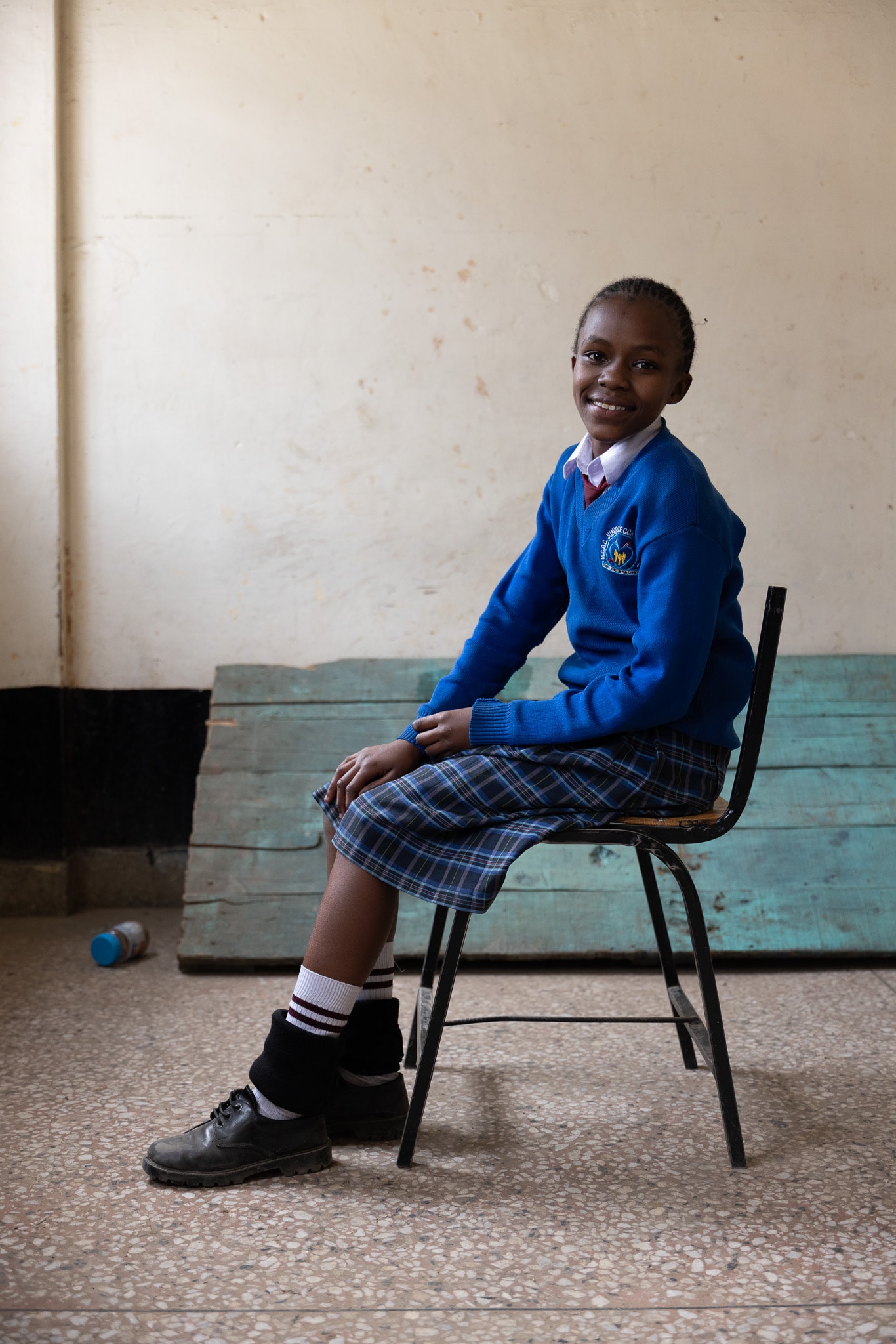 Student in blue school uniform seated, smiling at camera